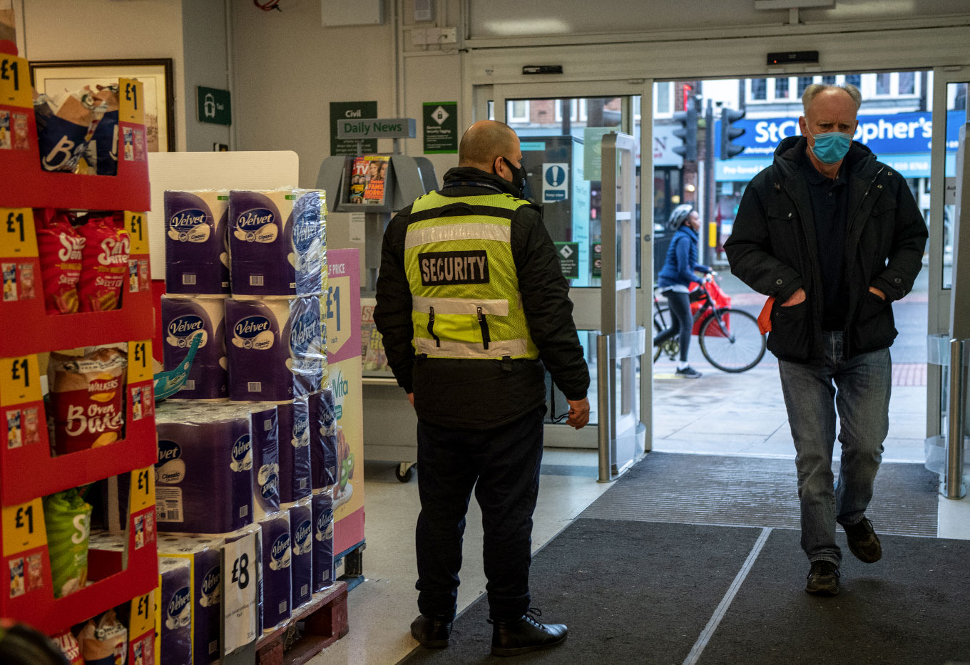 Photo of a security guard at entrance to a shop, taken from the inside looking out - Photo by Chris J Ratcliffe/Getty Images)